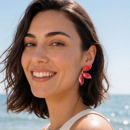 Smiling model at the beach wearing Canopy Ruby Glow red leaf earrings