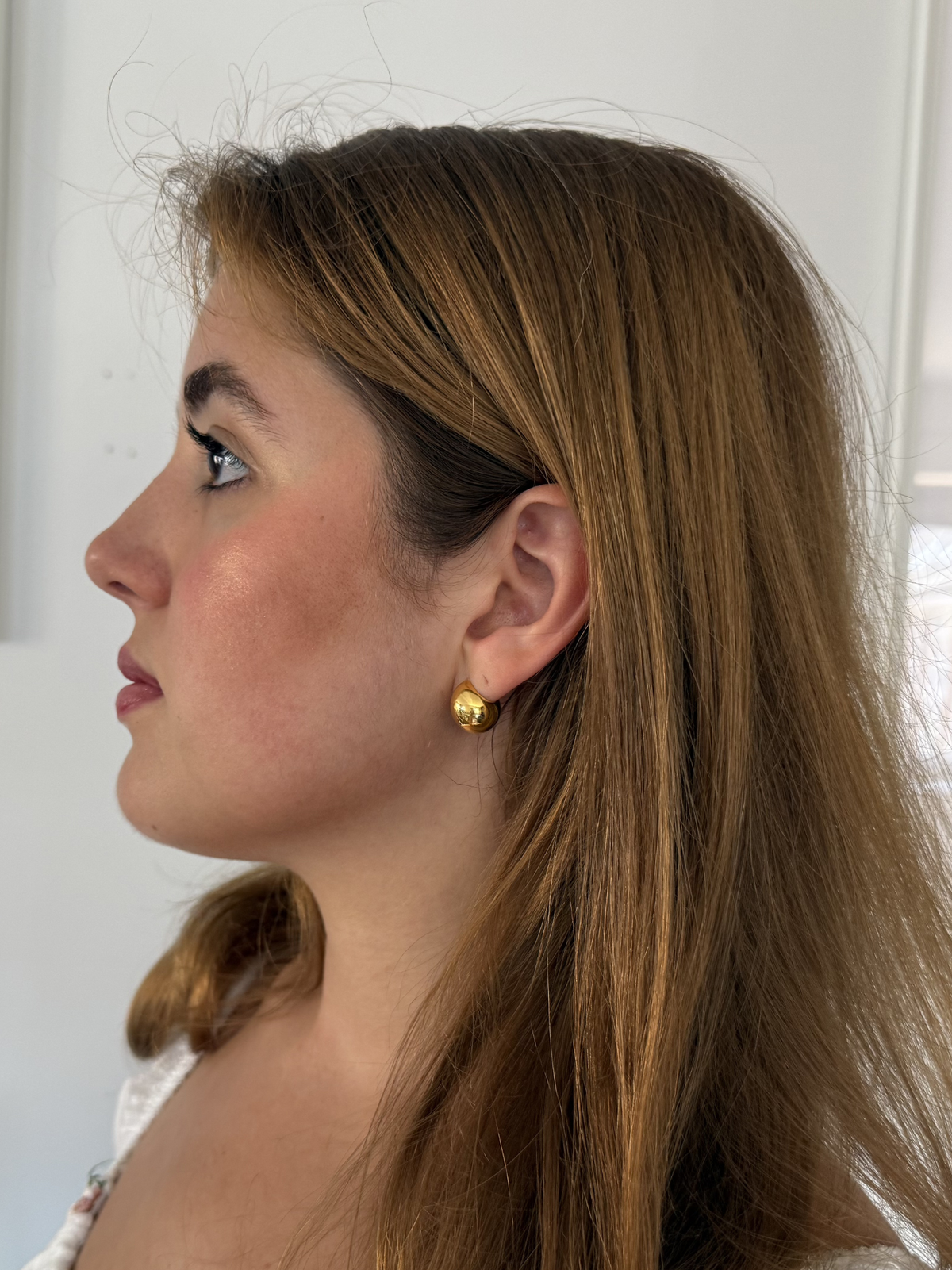 close up of a woman wearing gold round shaped earrings