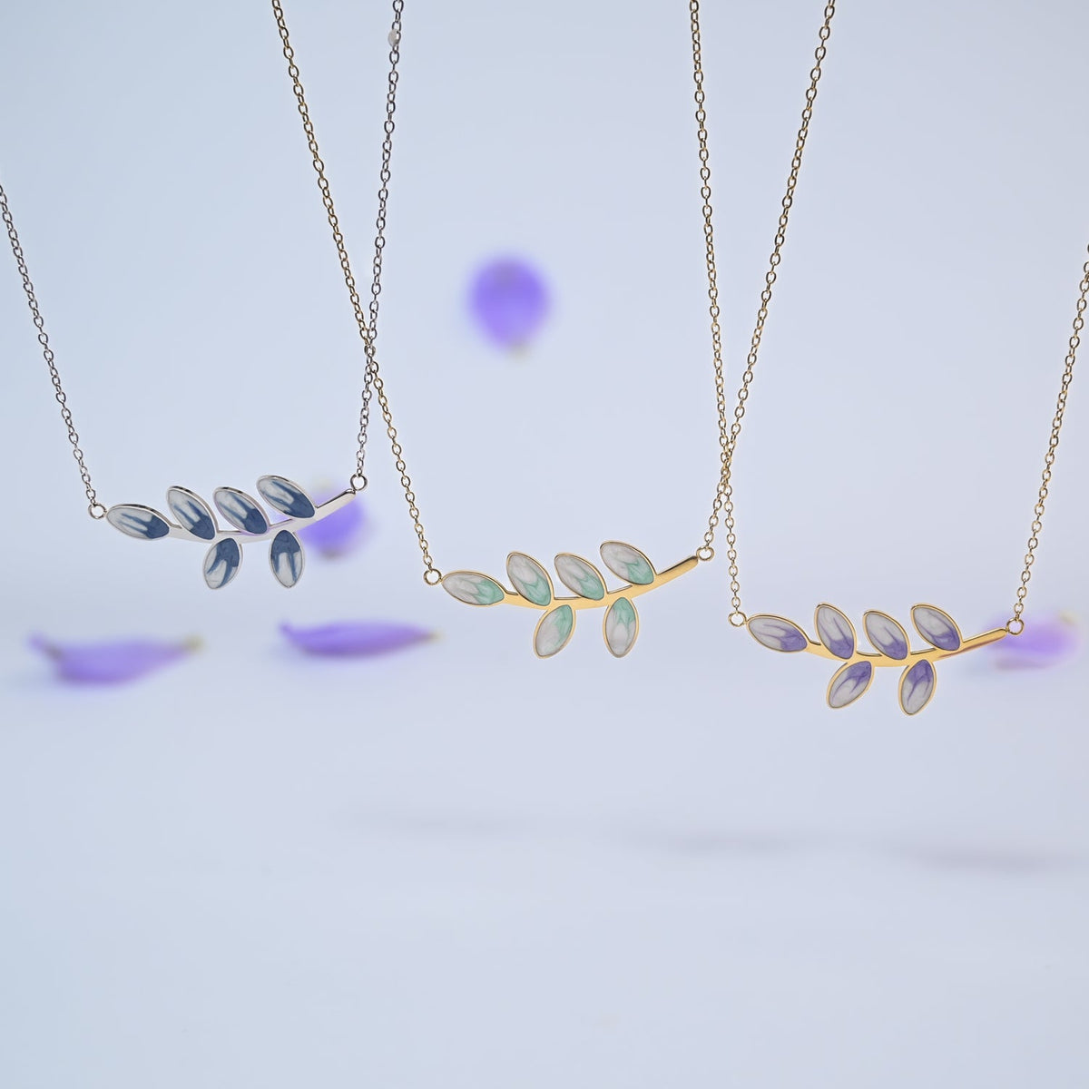 Three Hope Grows leaf necklaces in blue, mint and lavender among purple petals
