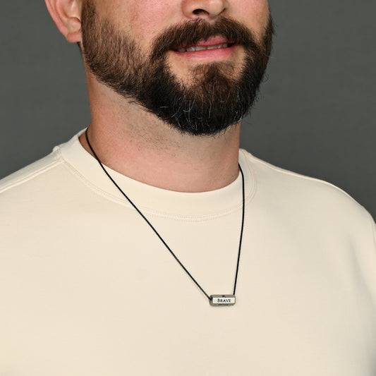 Close-up of bearded man wearing Pillar silver bar necklace on a black chain