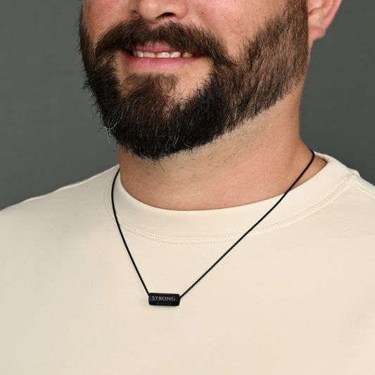 Bearded man wearing Pillar matte black bar necklace on black chain
