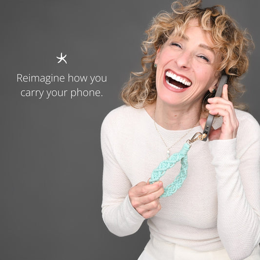 Laughing woman in a white sweater on the phone with Fresh Mint macramé wrist strap