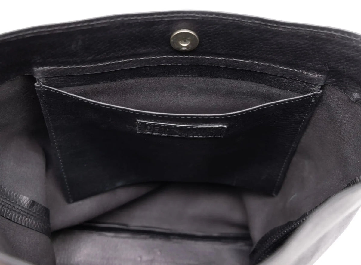 Close-up of a black leather bag with a visible brand logo.