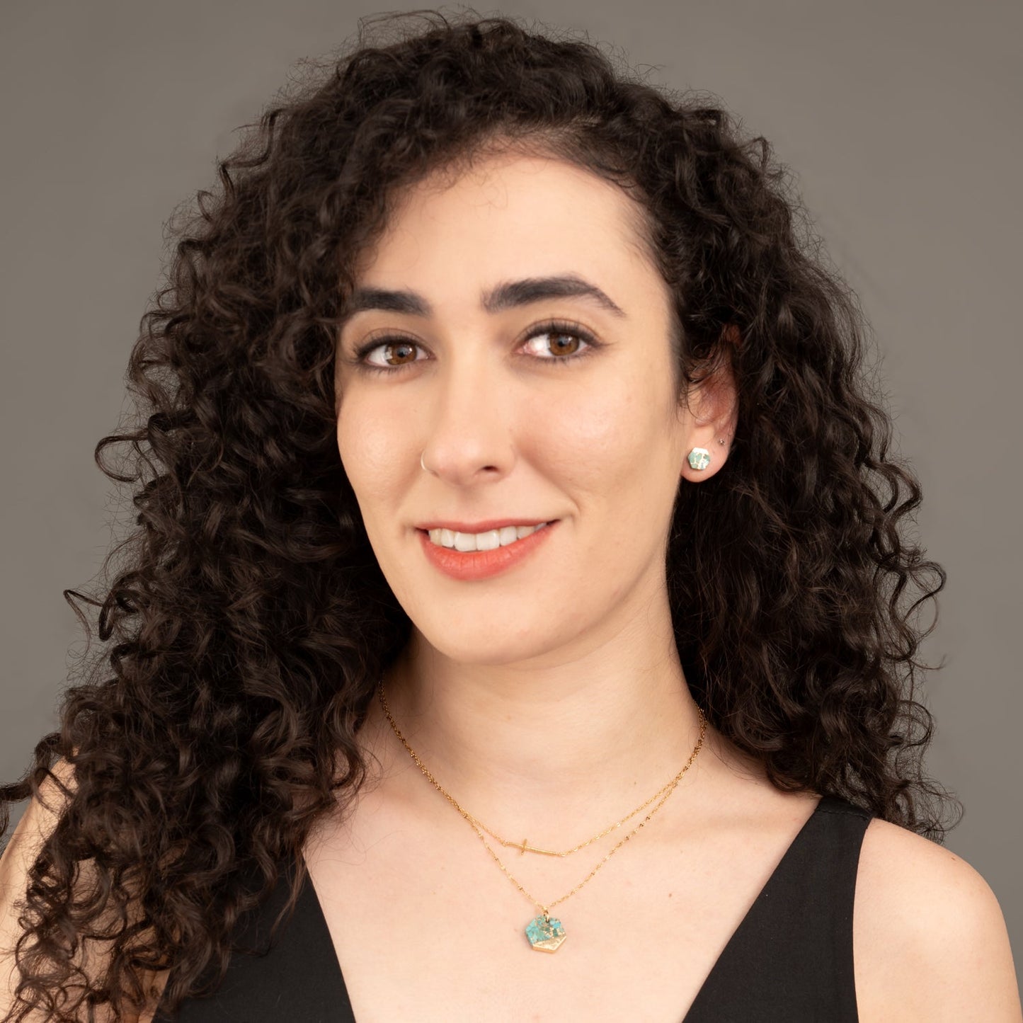 Woman layering gold cross necklace, matching green and gold jewelry, gold layering necklaces, women's jewelry company