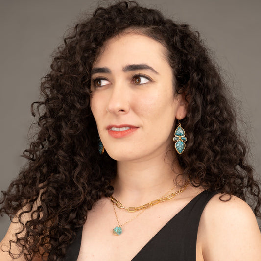 Woman wearing golden and turquoise matching jewelry, gold and blue pendant necklace, gold necklace with stone, fair trade groups