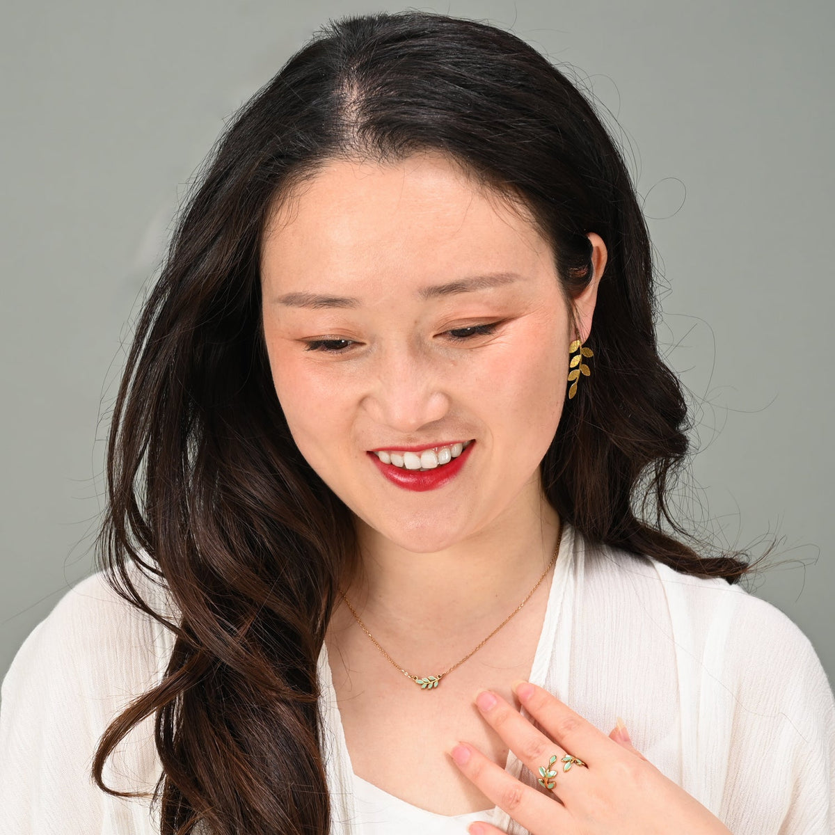 Smiling model wearing Rowen mint leaf necklace and matching earrings