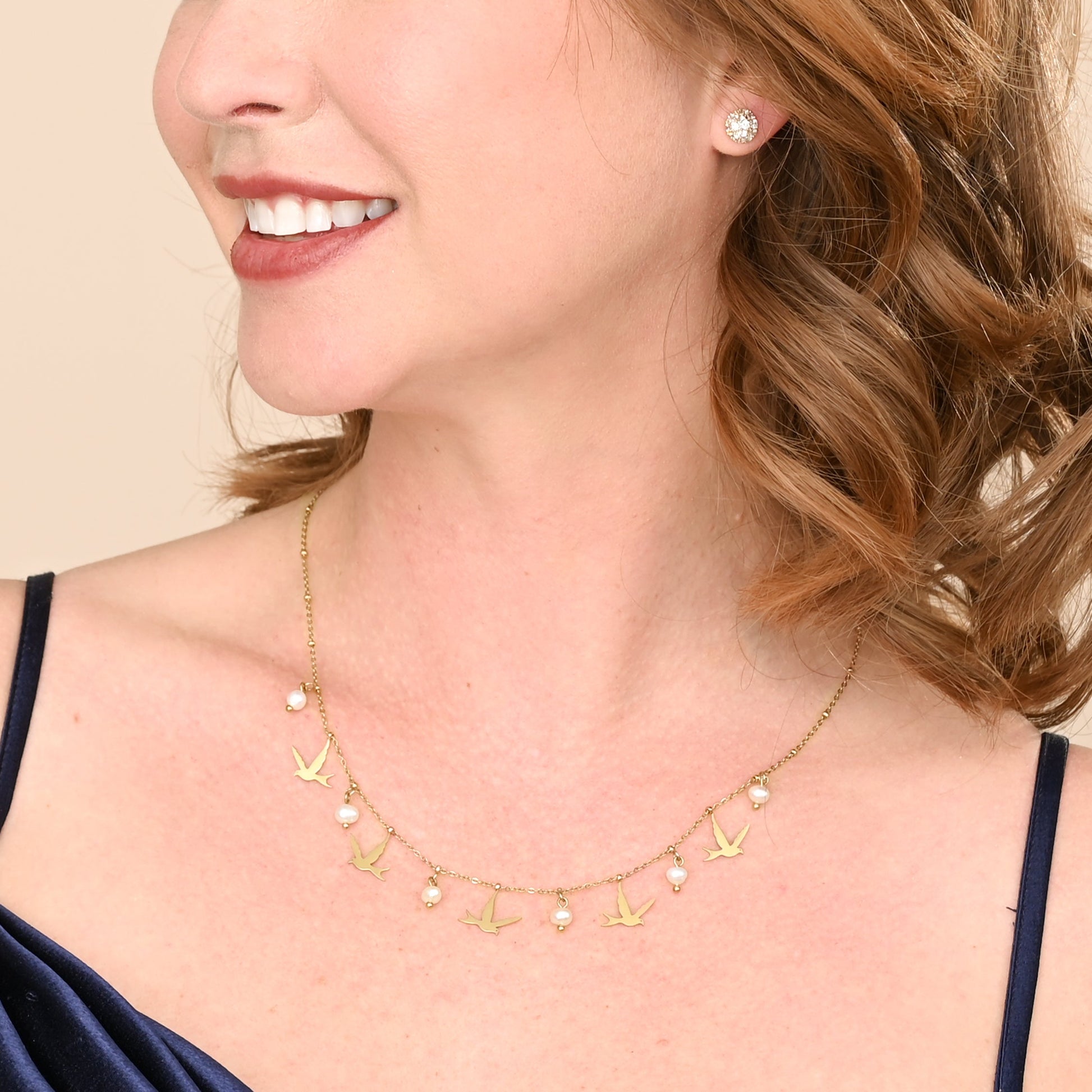 Woman wearing golden bird and pearl necklace, bird pendant necklace, gold necklace with pearls, fair trade groups