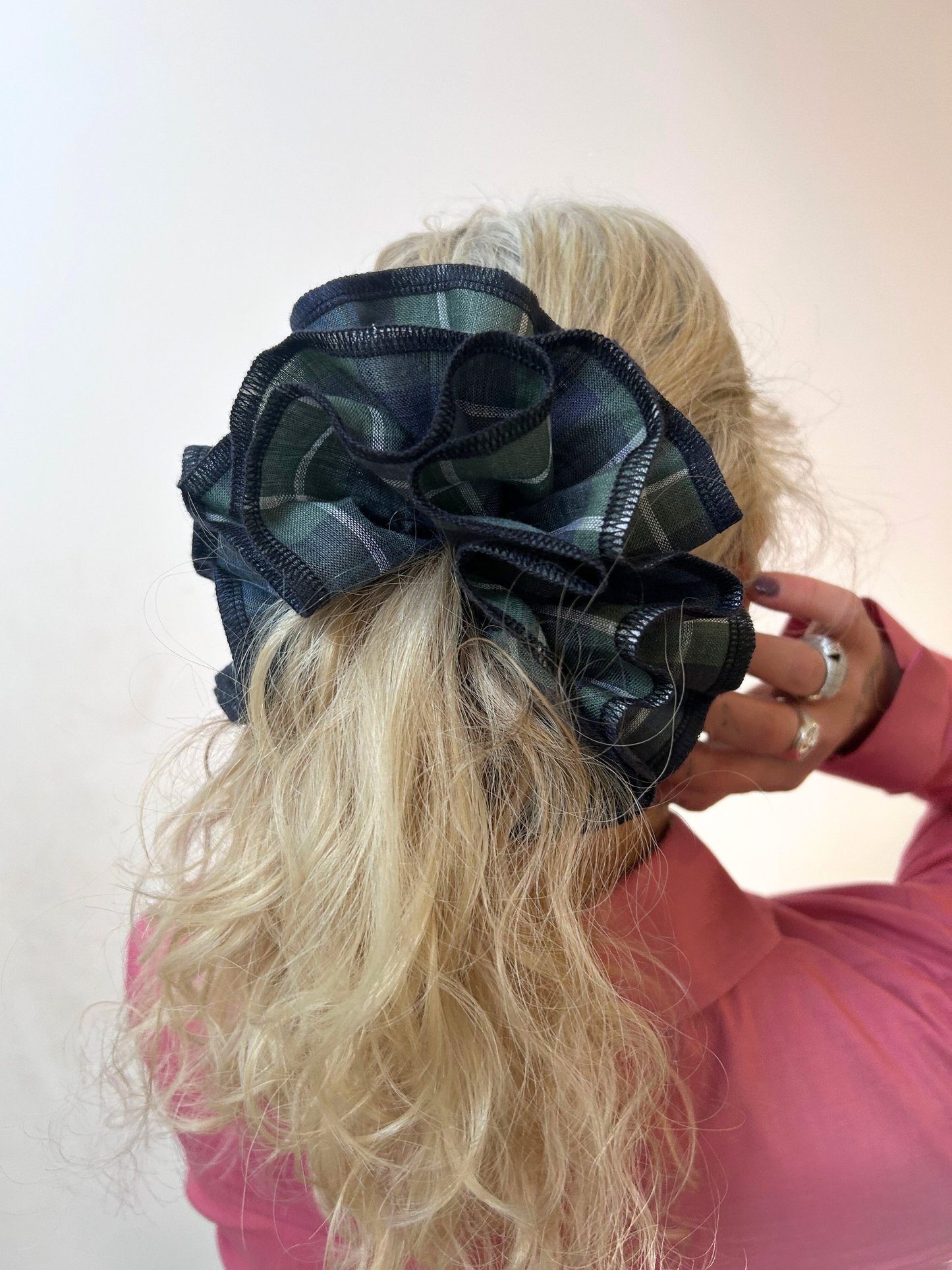 Person wearing a large navy and green plaid hair scrunchie against a white background