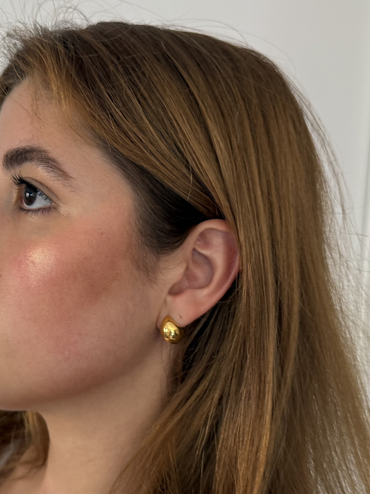 woman with dark straight hair wearing gold round shaped hoop earrings