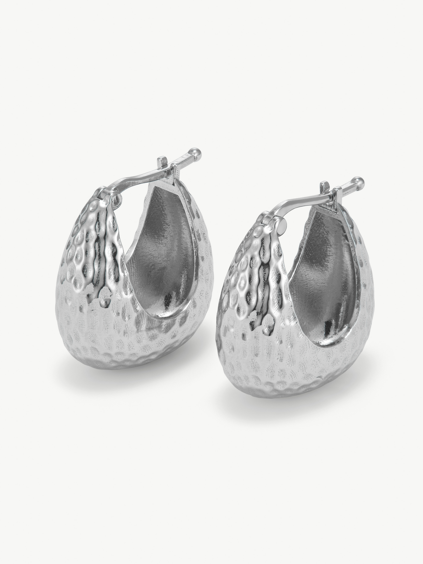 Pair of silver hoop hammered earrings on a white background