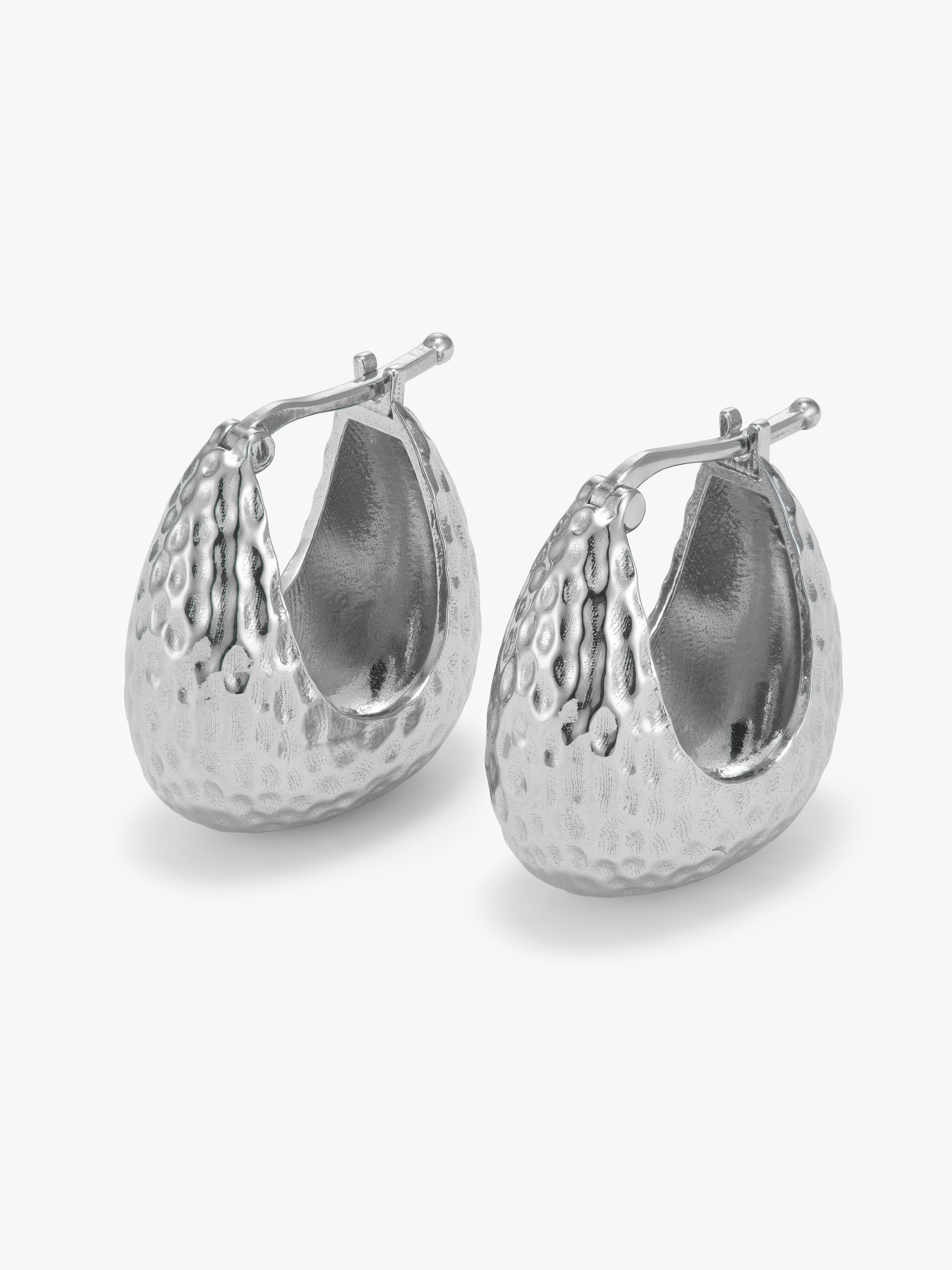Pair of silver hoop hammered earrings on a white background