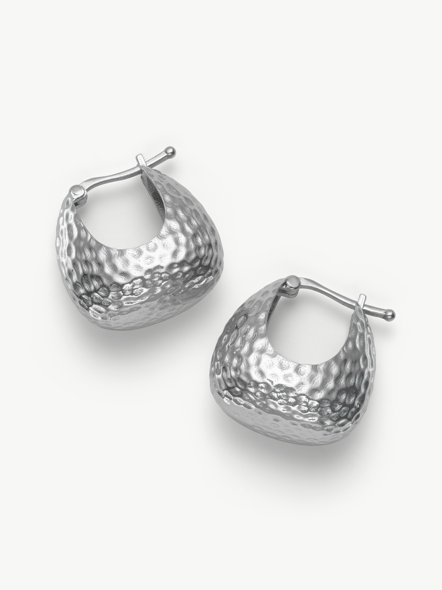 Pair of silver hoop hammered earrings on a white background