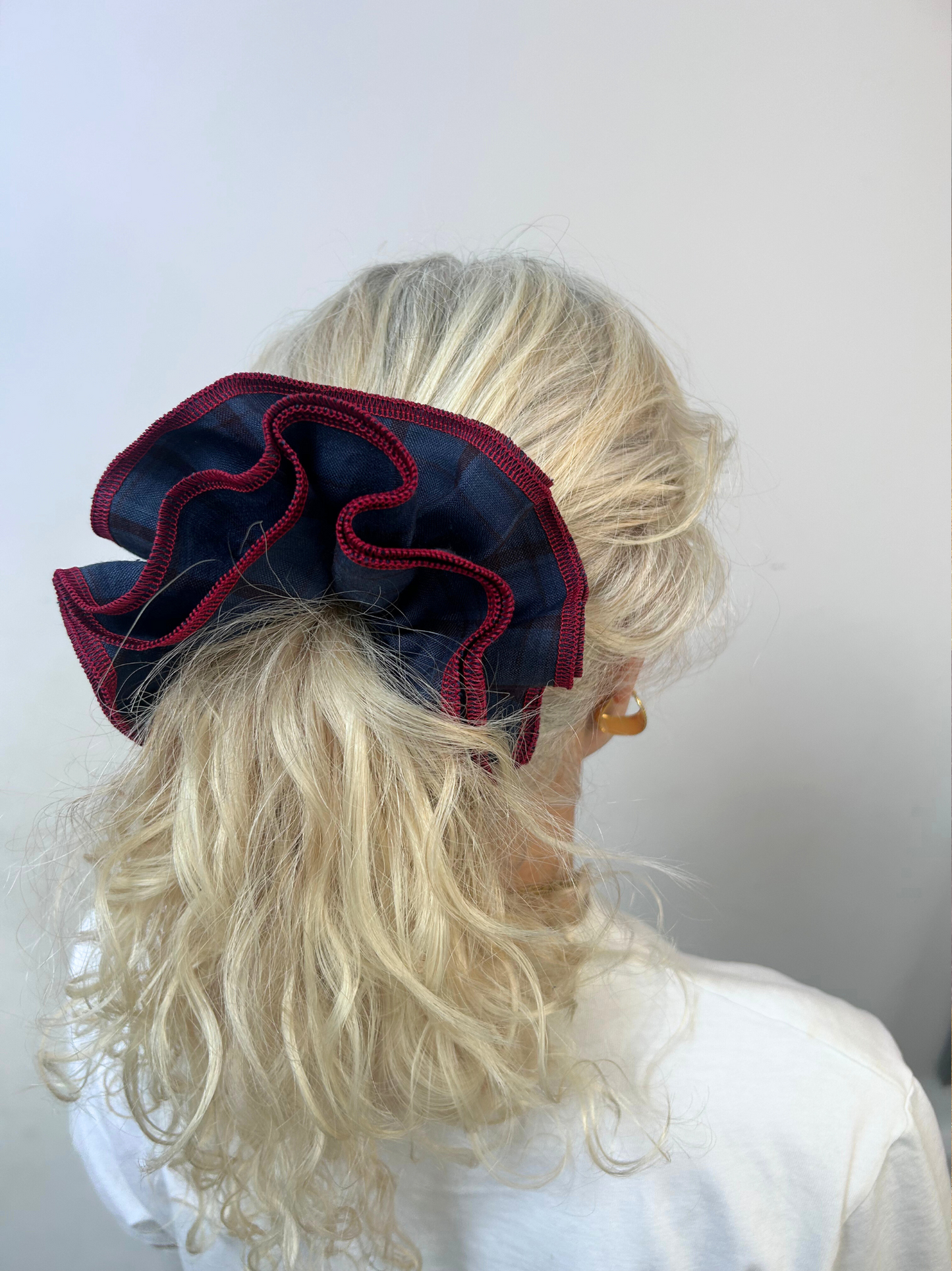 Person with blonde hair wearing a large red and navy hair bow against a white background