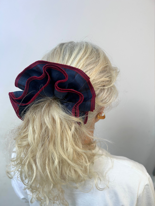 Person with blonde hair wearing a large red and navy hair bow against a white background