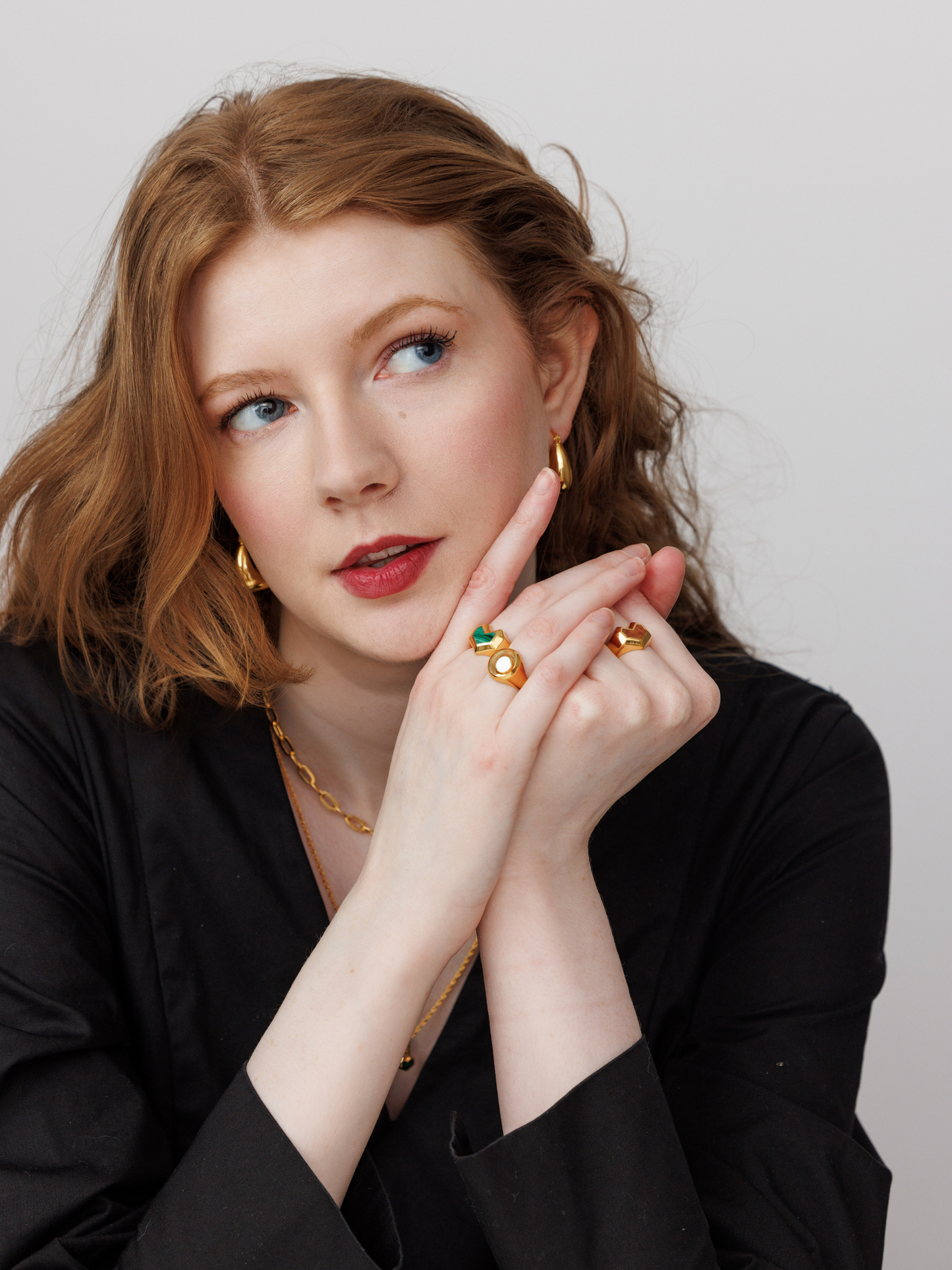 Woman wearing gold jewelry against a neutral background