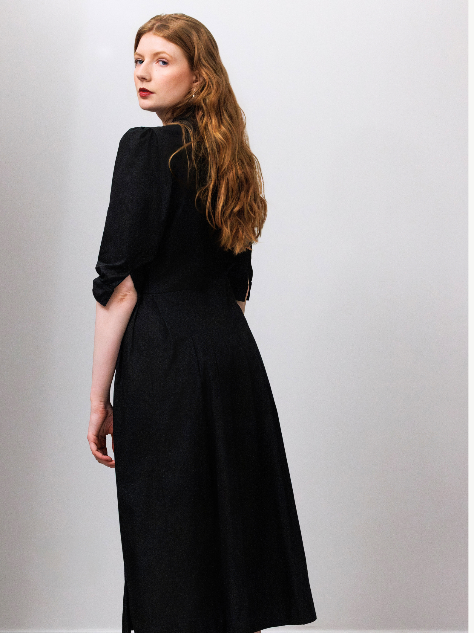 Woman wearing a black dress against a plain background