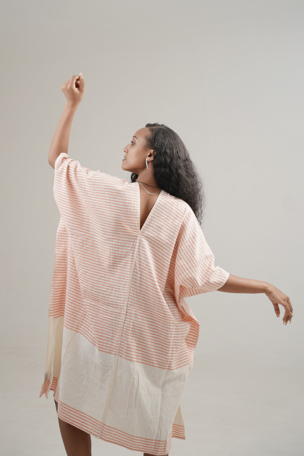 Ari kaftan in salmon facinb backwards on ethiopian model 