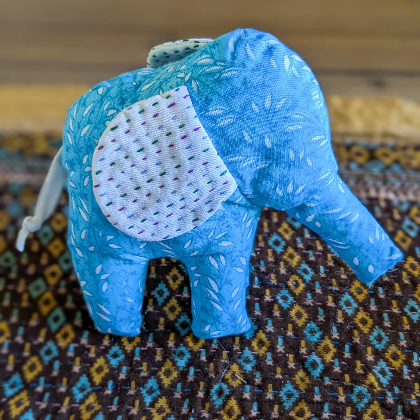 Blue elephant plush on a patterned fabric background