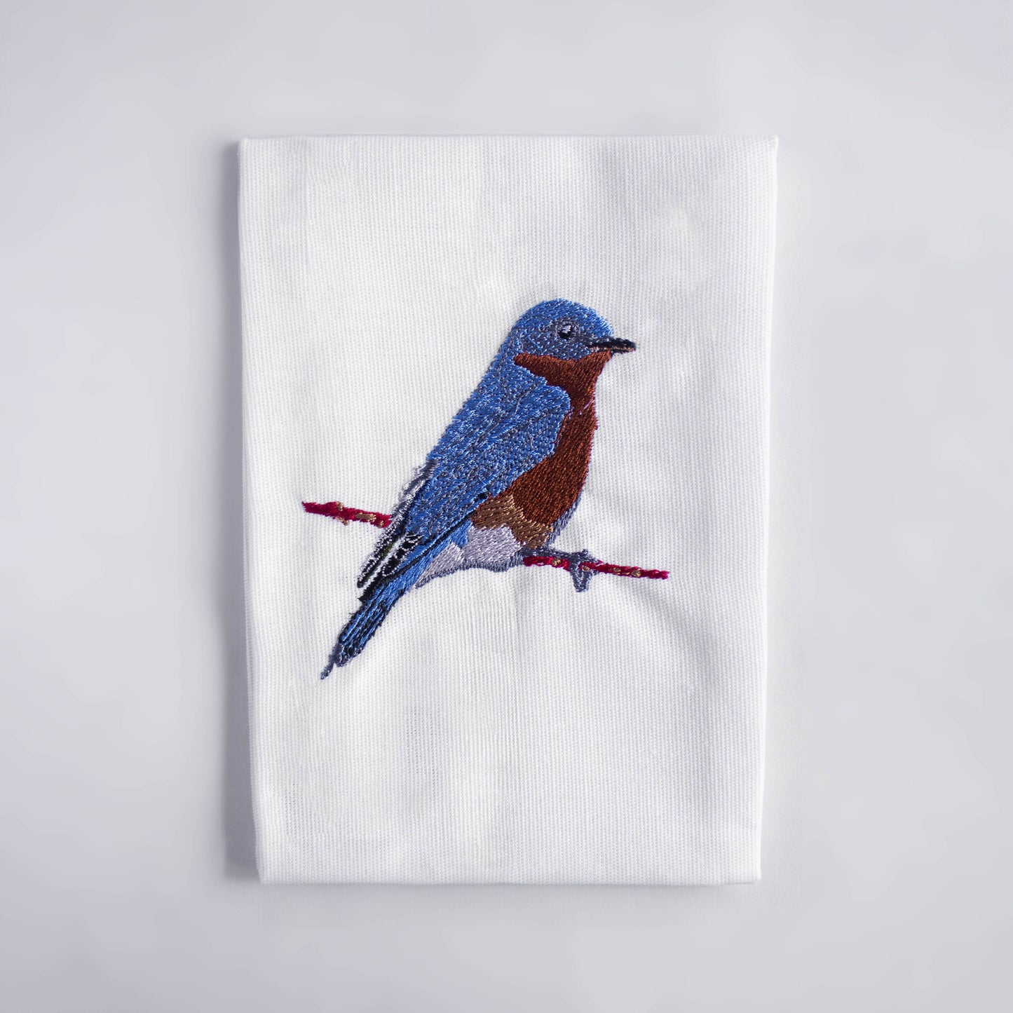 Bluebird embroidered cotton cloth napkin flat lay on white surface