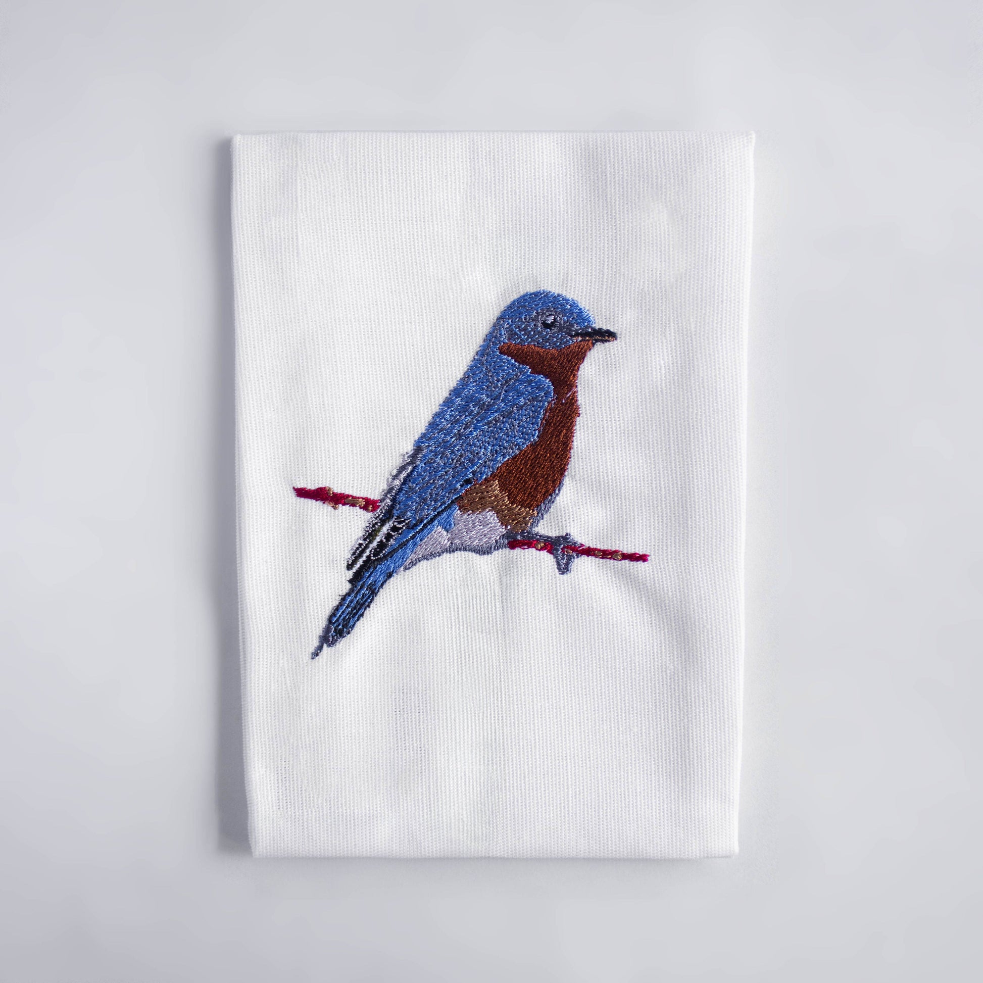 Bluebird embroidered cotton cloth napkin flat lay on white surface