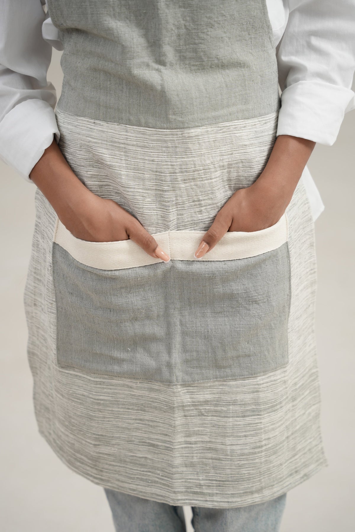 Close up on pockets of Apron in grey on ethiopian model with white background