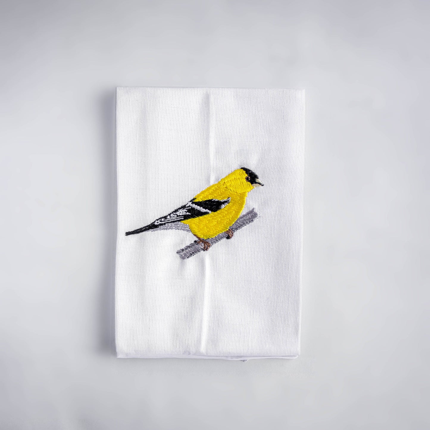 Goldfinch embroidered cotton cloth napkin flat lay on white