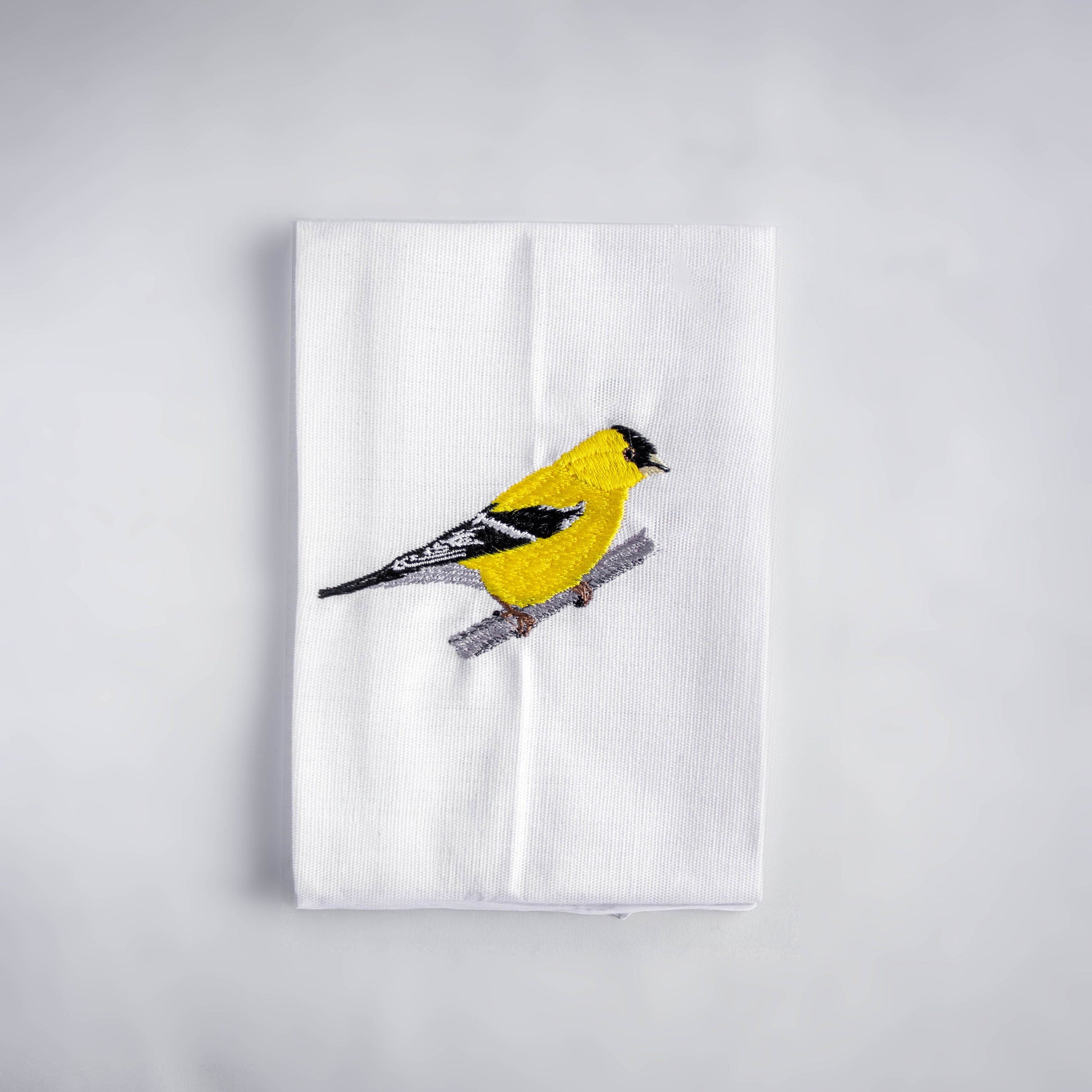 Goldfinch embroidered cotton cloth napkin flat lay on white