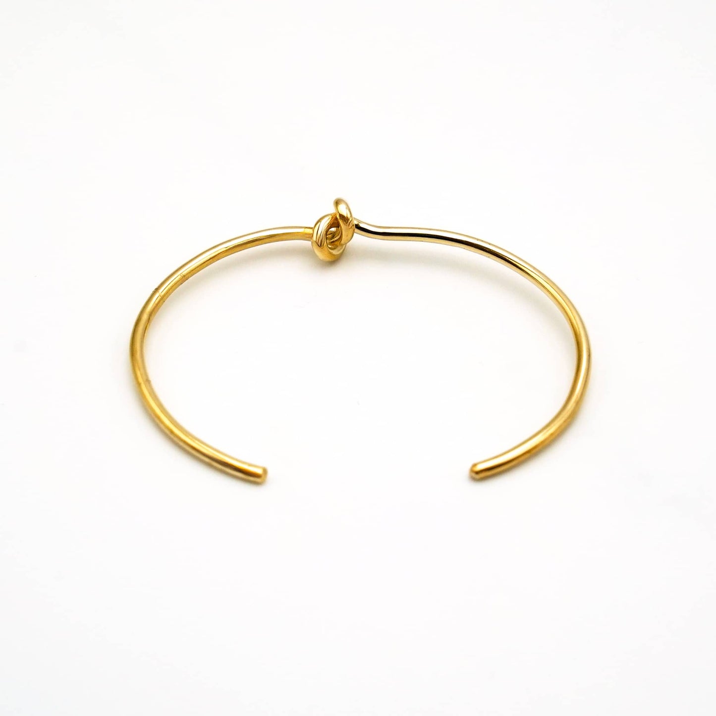Tatu knot brass choker necklace flat lay on warm surface — Ecodunia