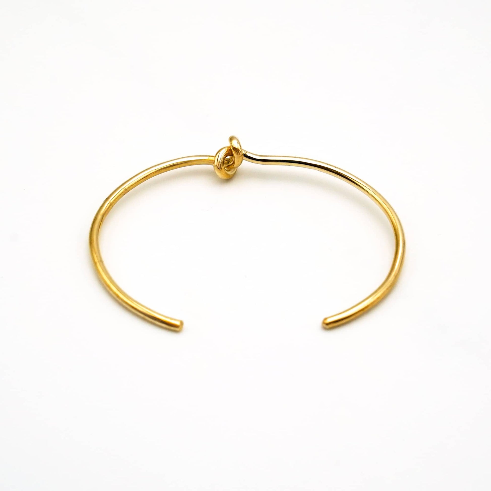 Tatu knot brass choker necklace flat lay on warm surface — Ecodunia