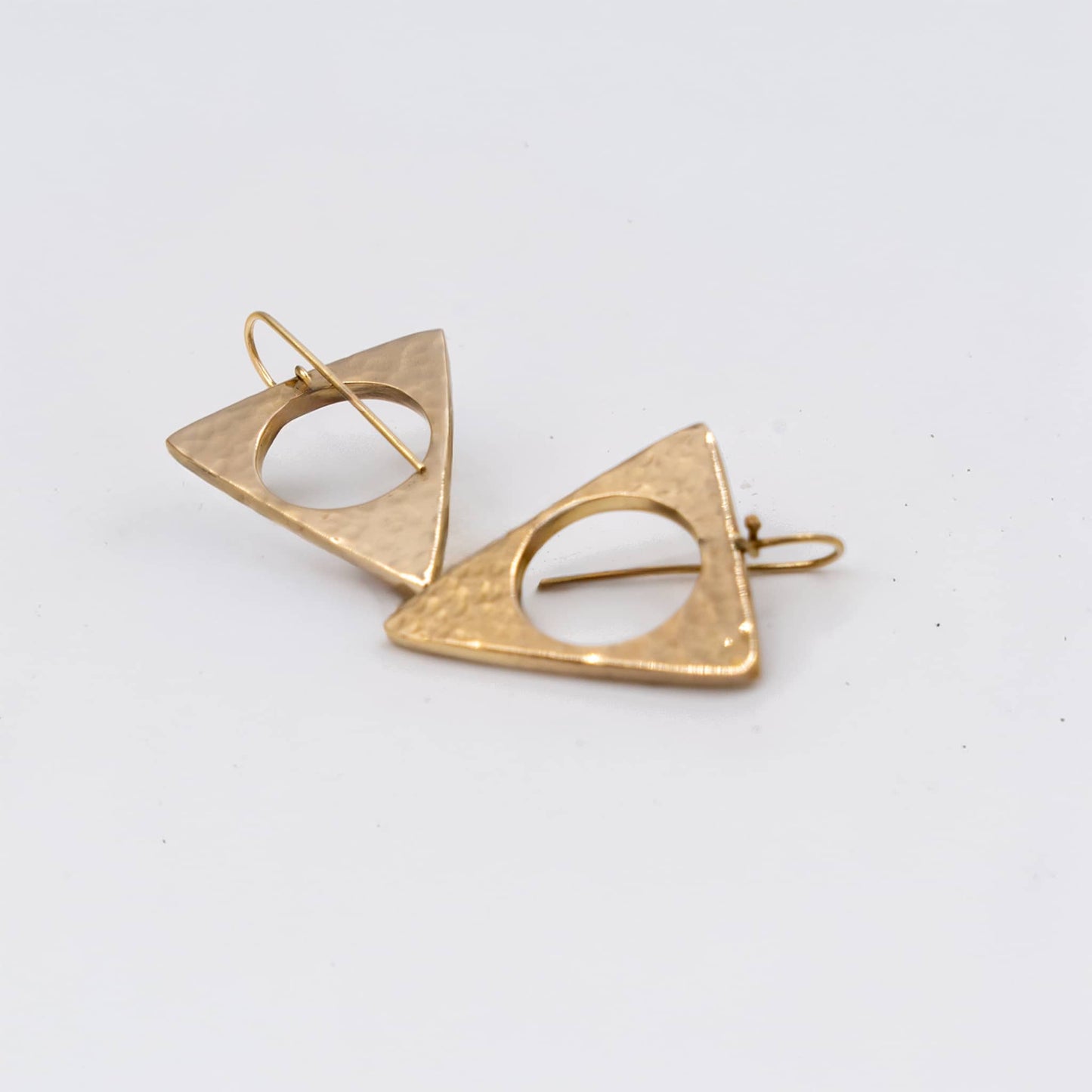 Lia hammered hollow triangle earrings flat lay showing texture