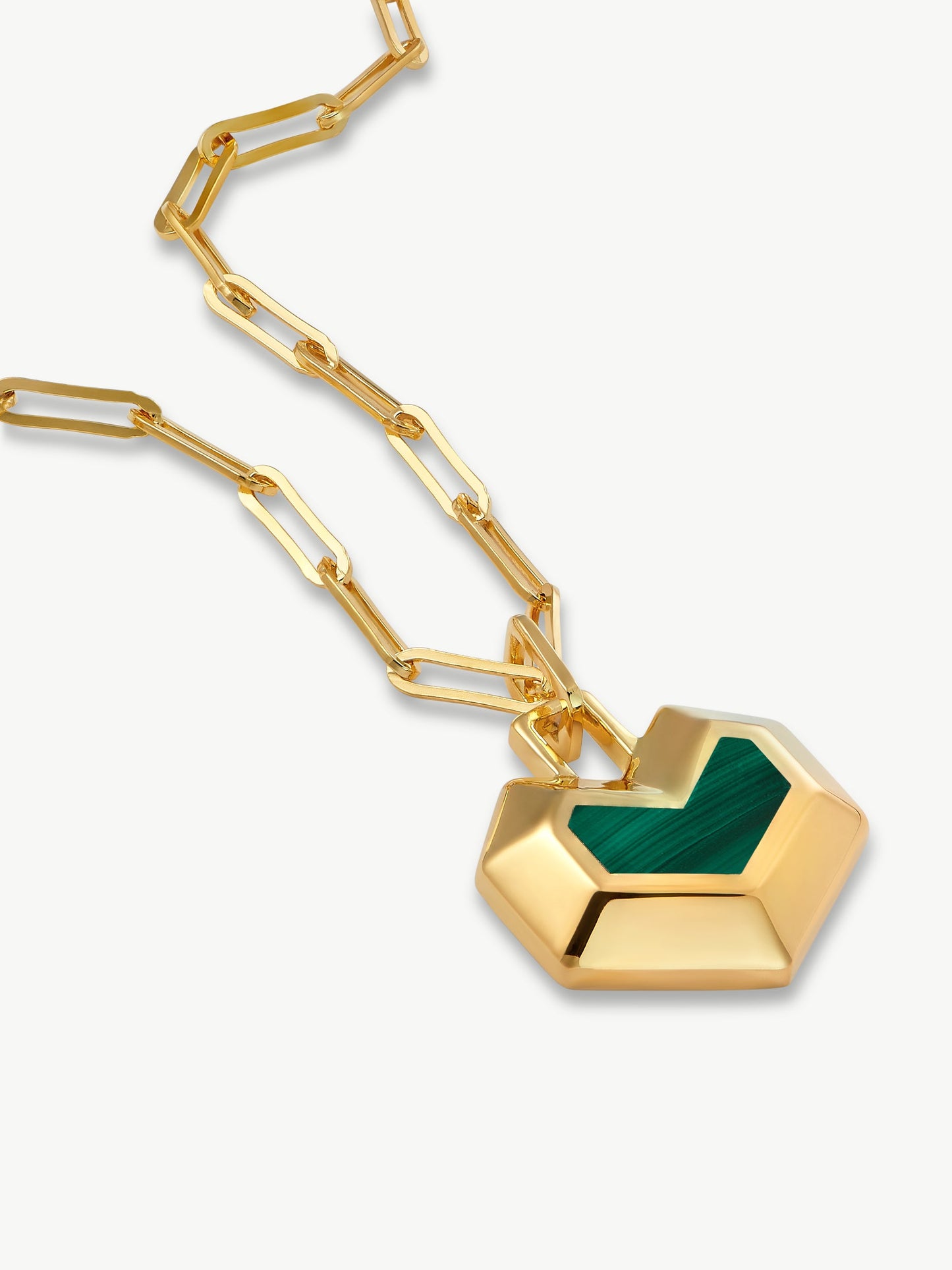 Gold necklace with a green heart pendant on a white background
