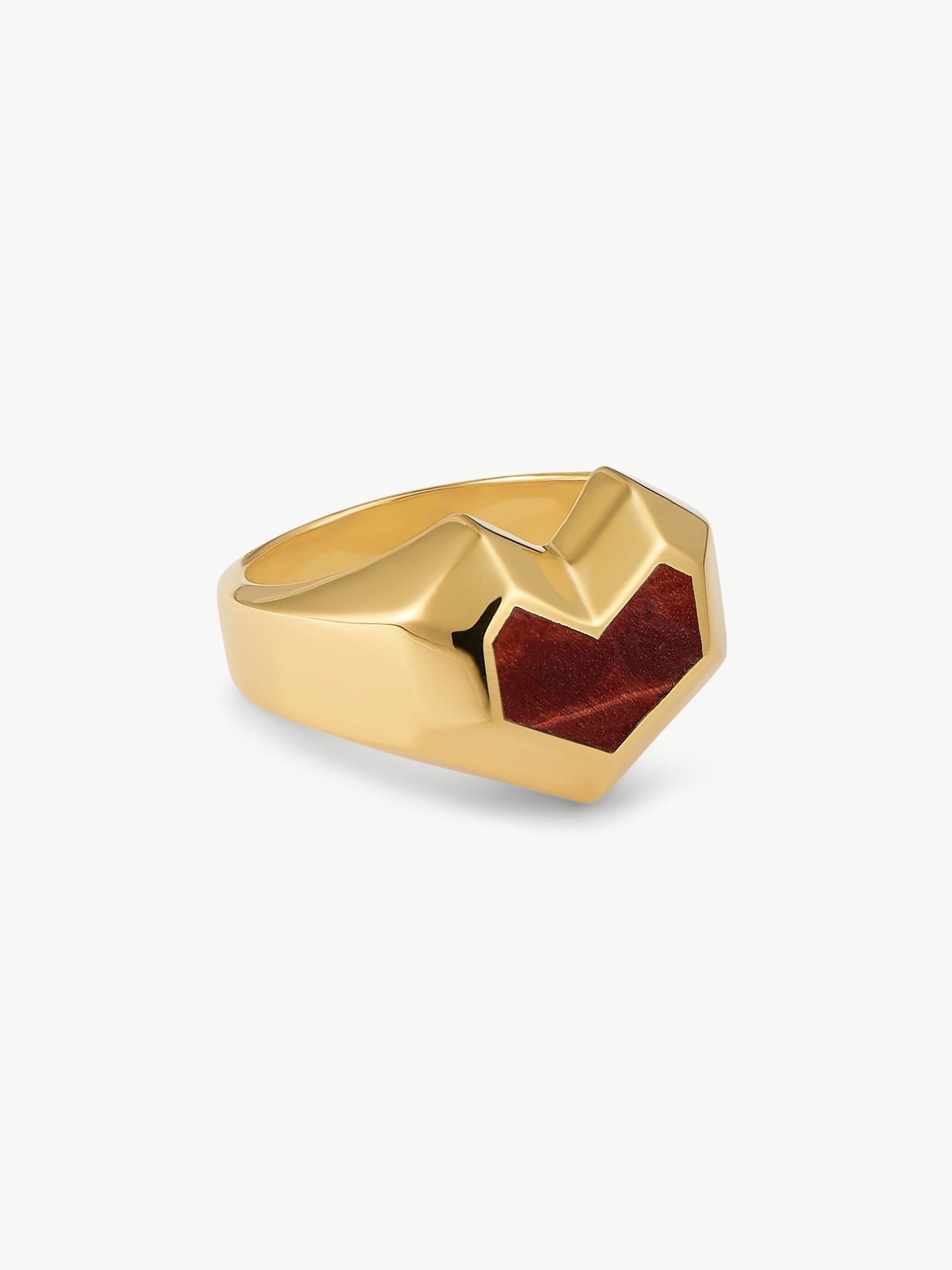 Gold ring with a heart red stone on a white background