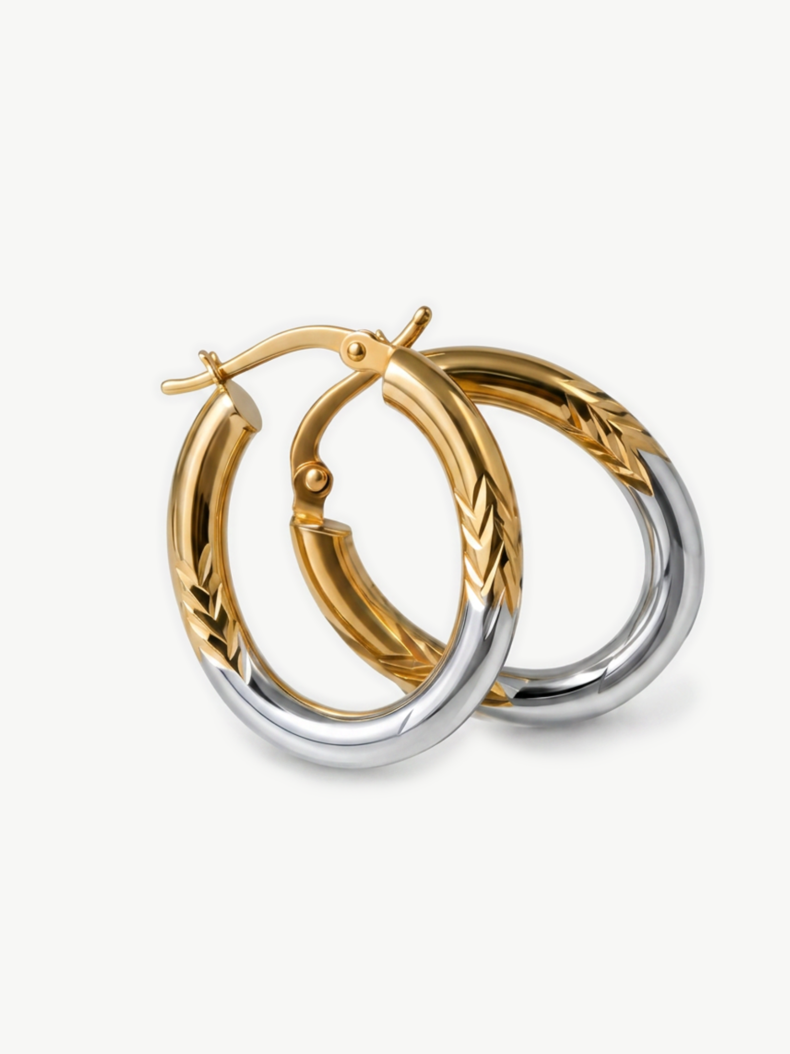 Two gold and silver hoop earrings on a white background