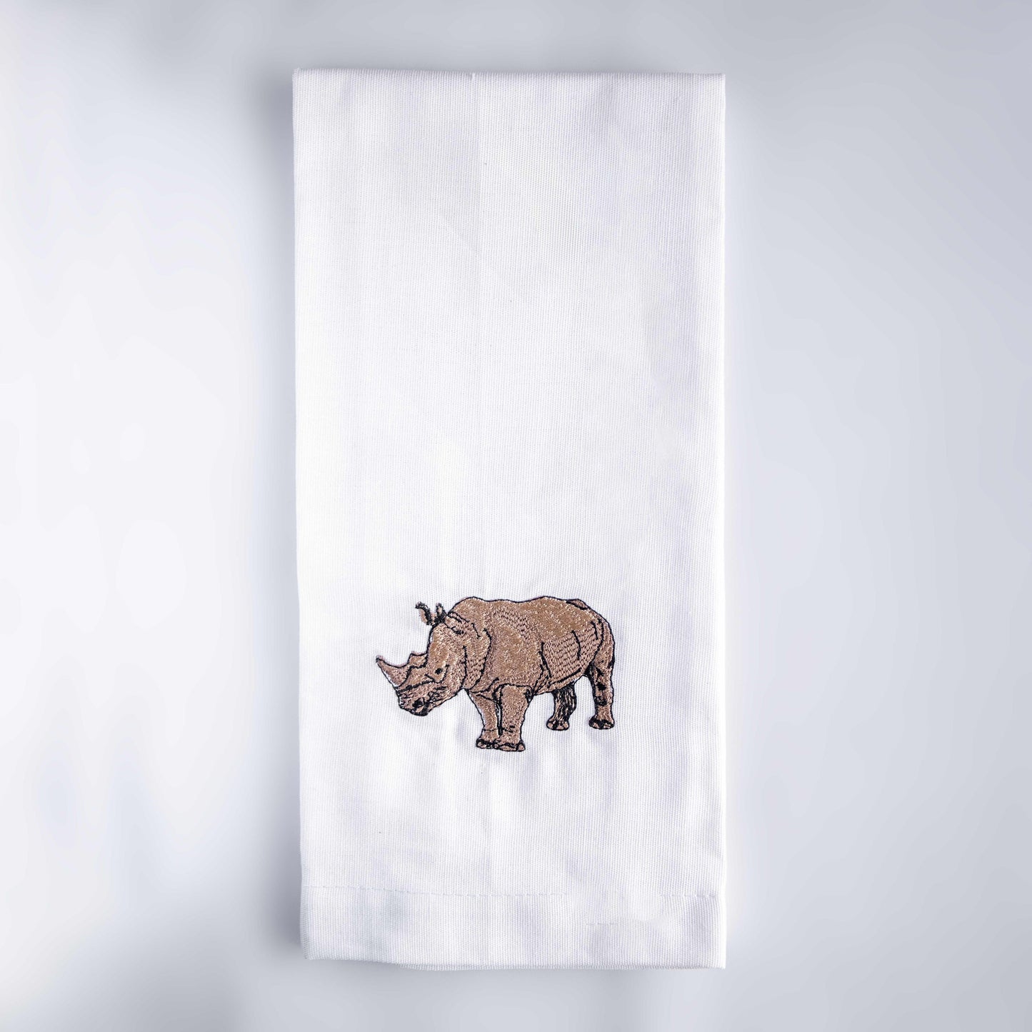 Rhino embroidered cotton kitchen tea towel on white surface