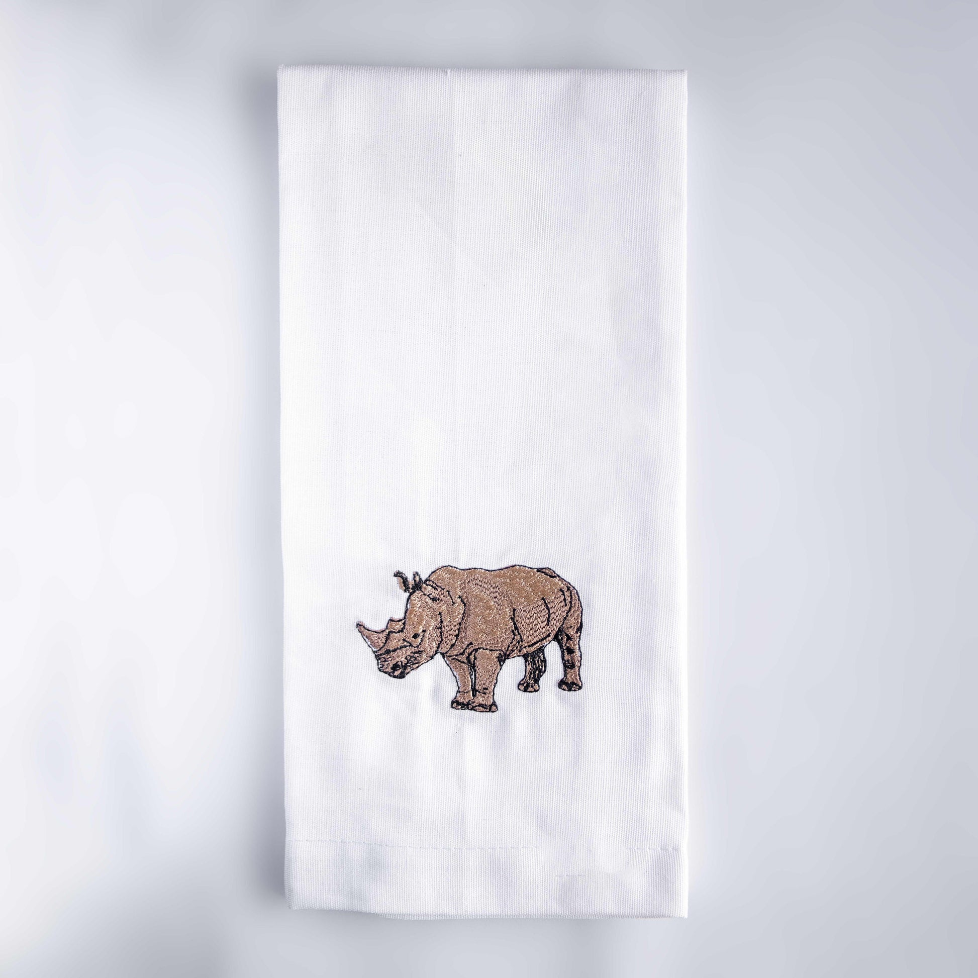 Rhino embroidered cotton kitchen tea towel on white surface