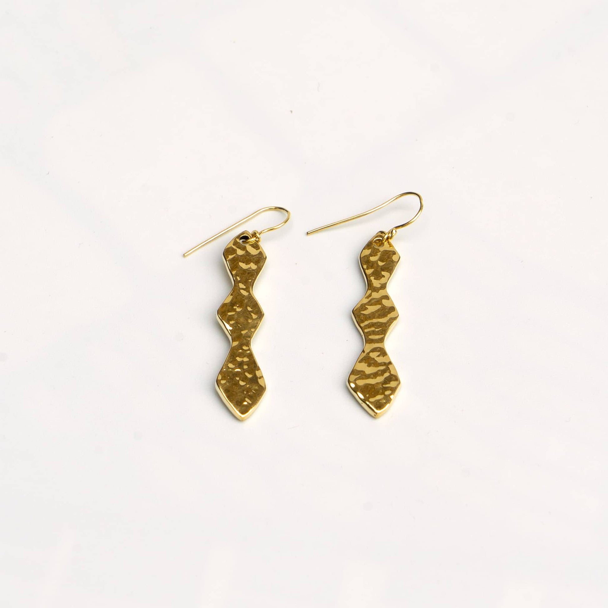Rio hammered double hourglass brass dangle earrings flat lay — Ecodunia