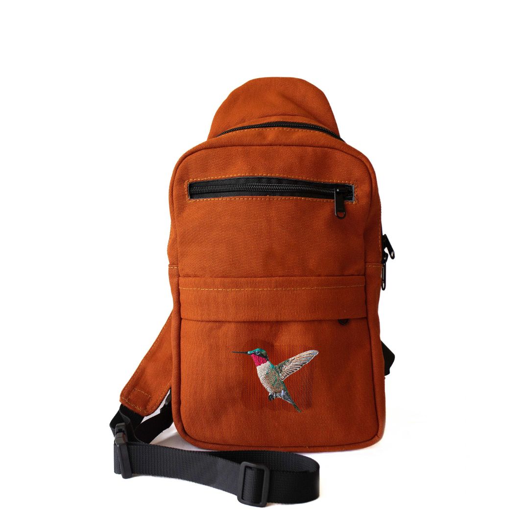 Umoja hummingbird embroidered rust canvas sling bag flat lay #color_rust