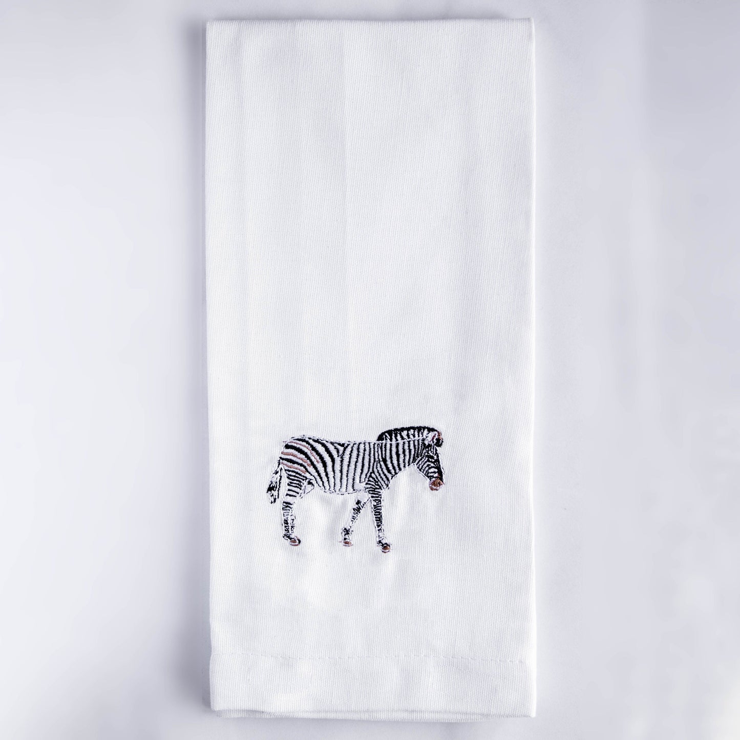 Zebra embroidered cotton kitchen tea towel flat lay on white