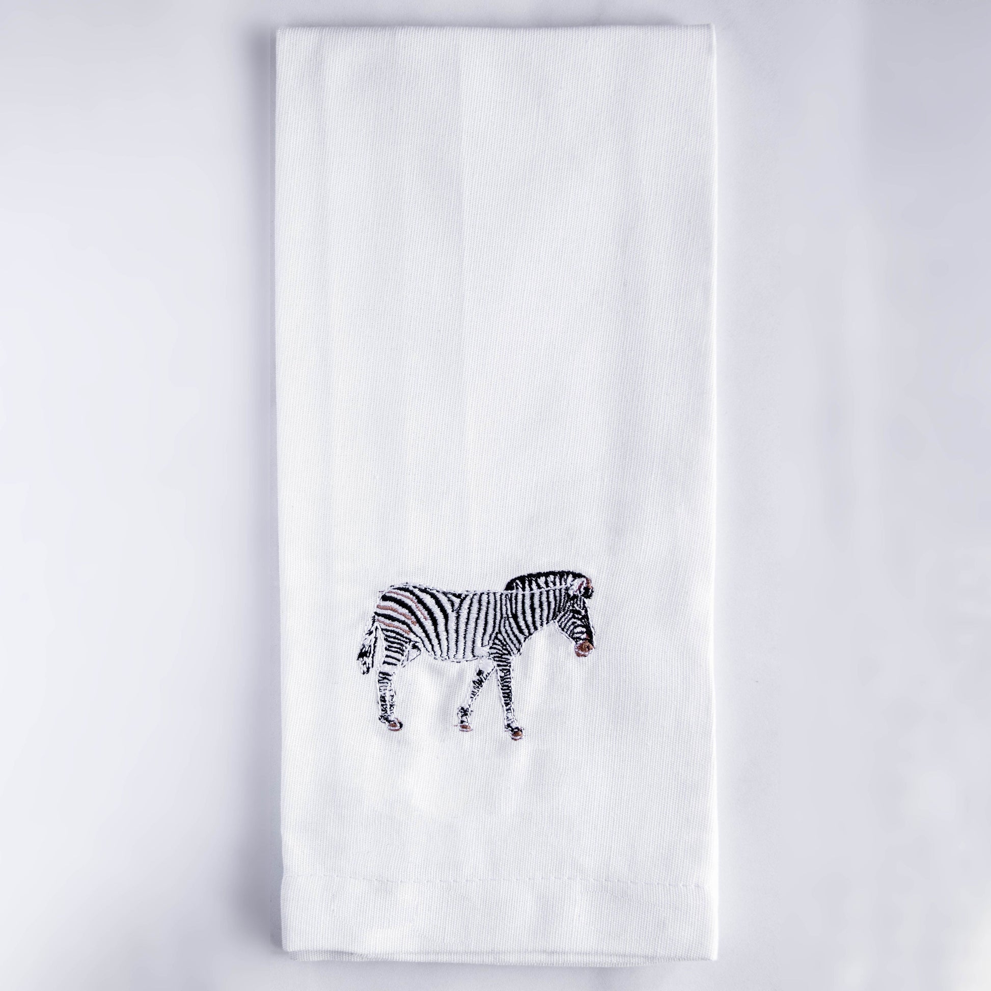 Zebra embroidered cotton kitchen tea towel flat lay on white