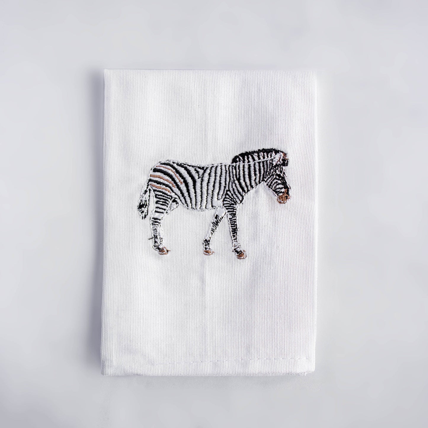 Zebra embroidered cotton dinner napkin flat lay on white