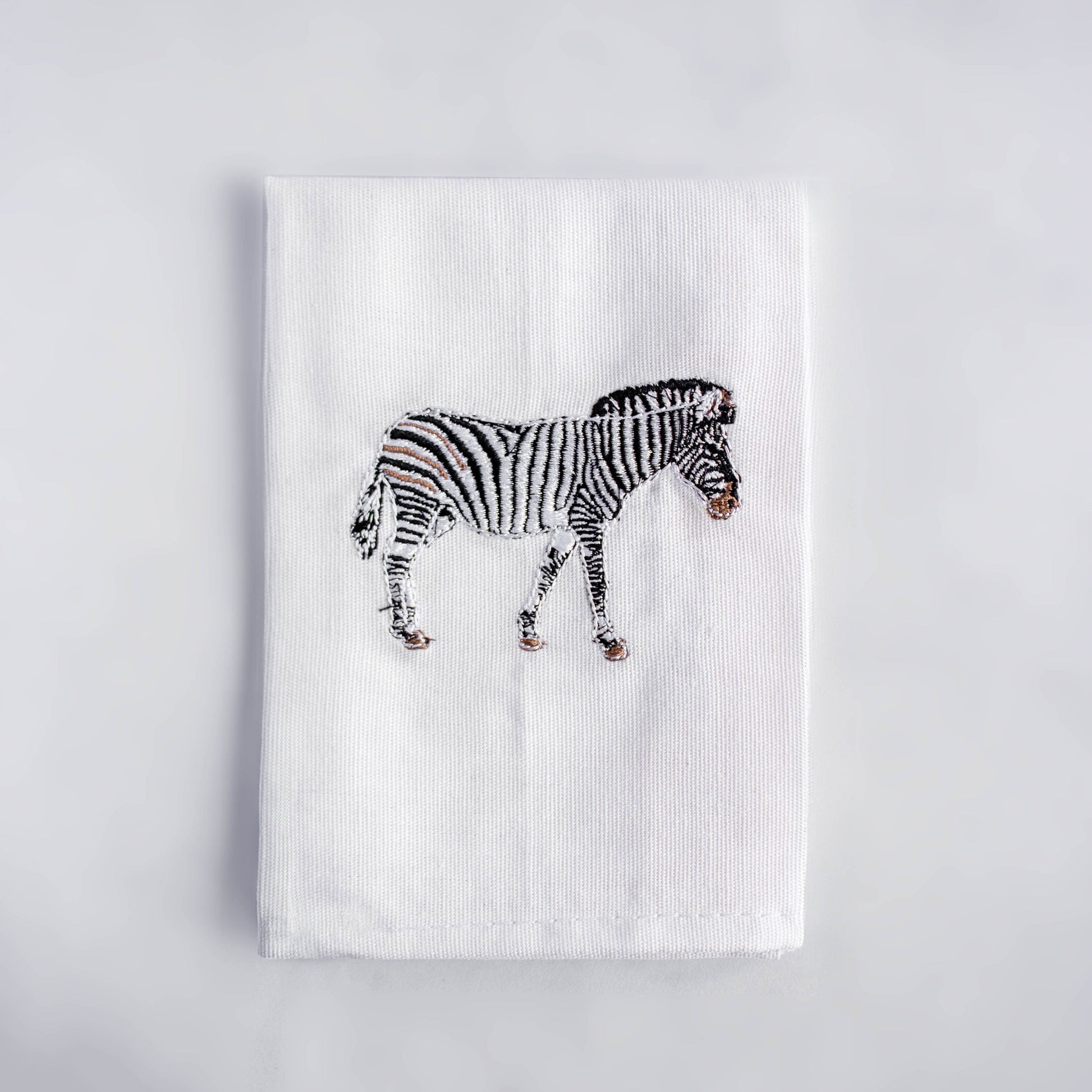 Zebra embroidered cotton dinner napkin flat lay on white