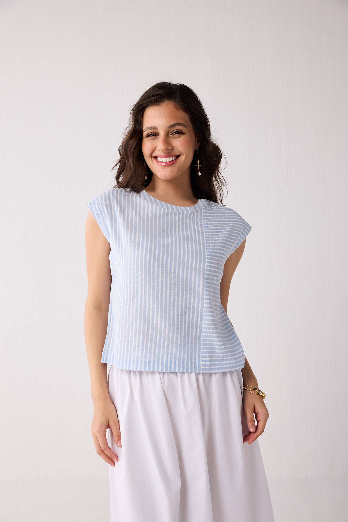 A woman wearing a light blue striped top against a plain background
