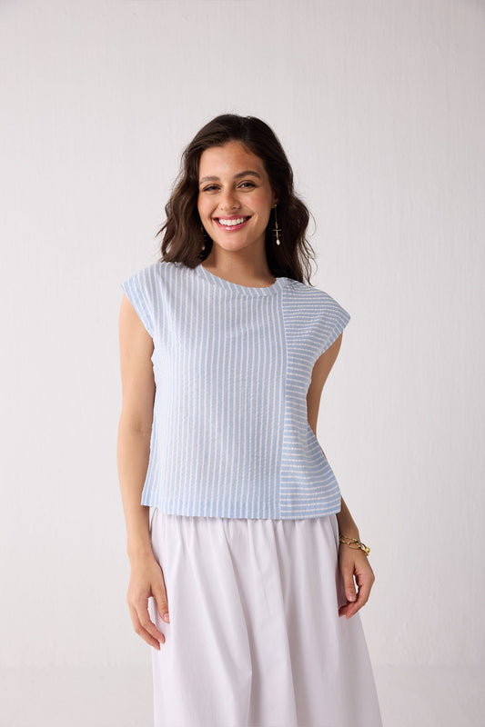 A woman wearing a light blue striped top against a plain background