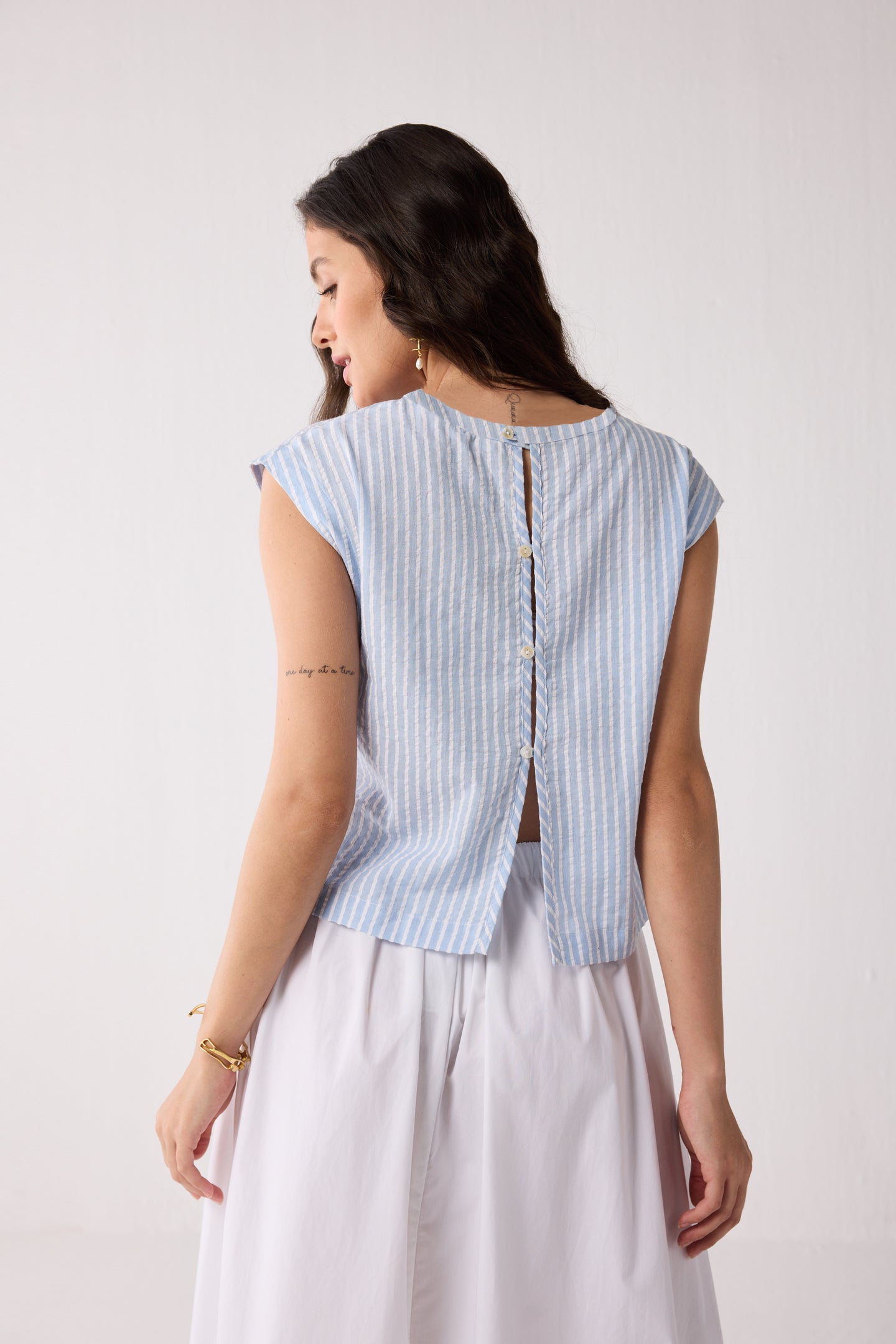 Woman wearing a light blue striped top with a white background