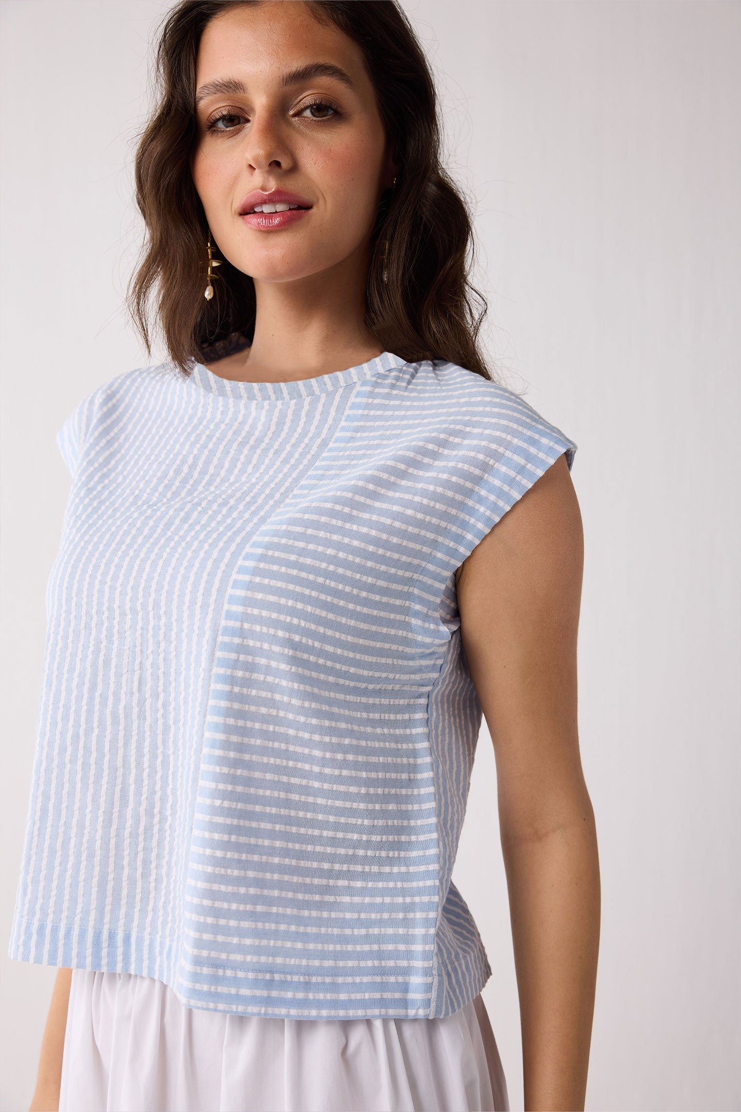 Woman wearing a light blue striped top against a white background