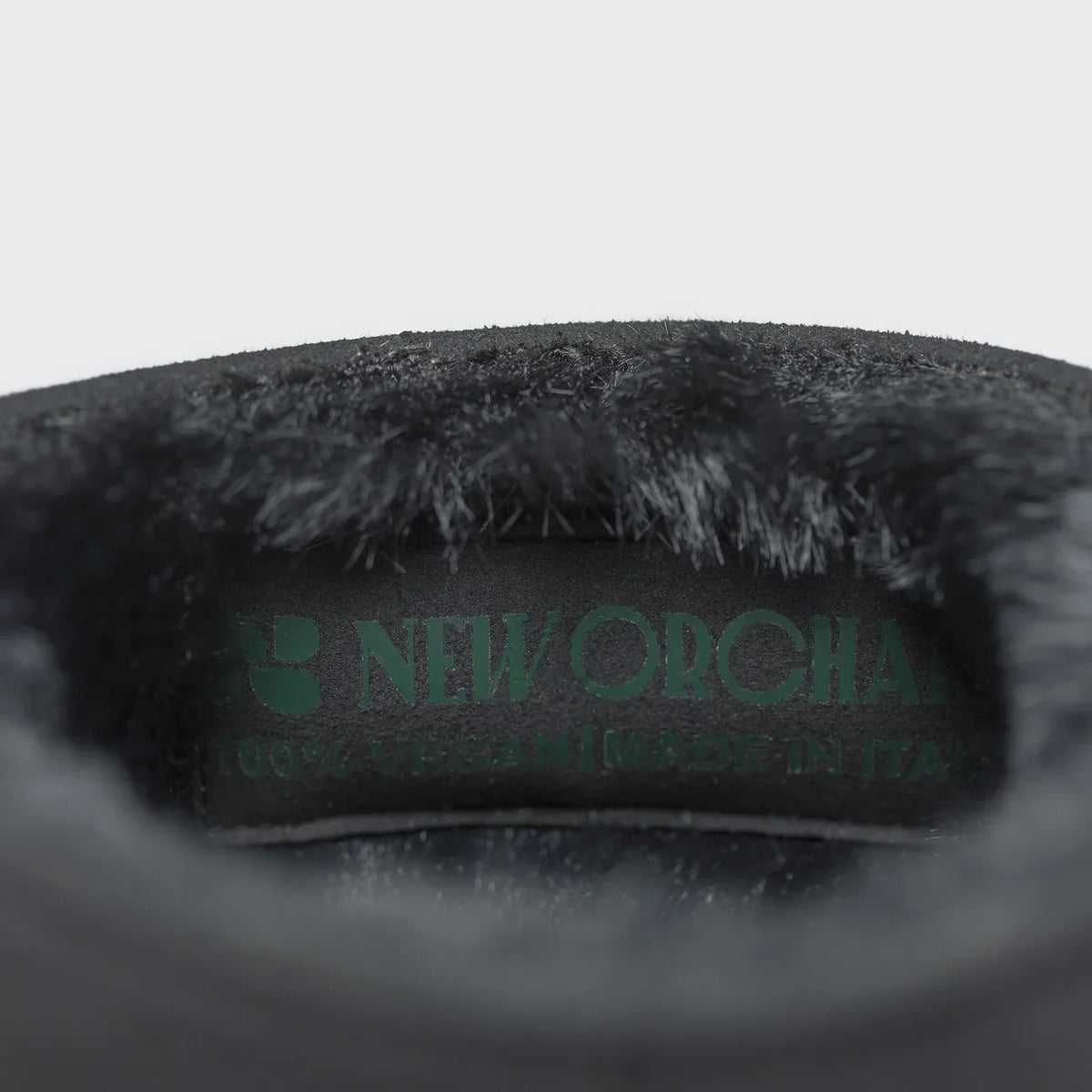 Close-up on boots of a dark gray plush item branding on a light gray background