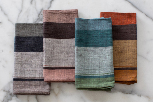 Four dalol napkins in different colors on a marble surface