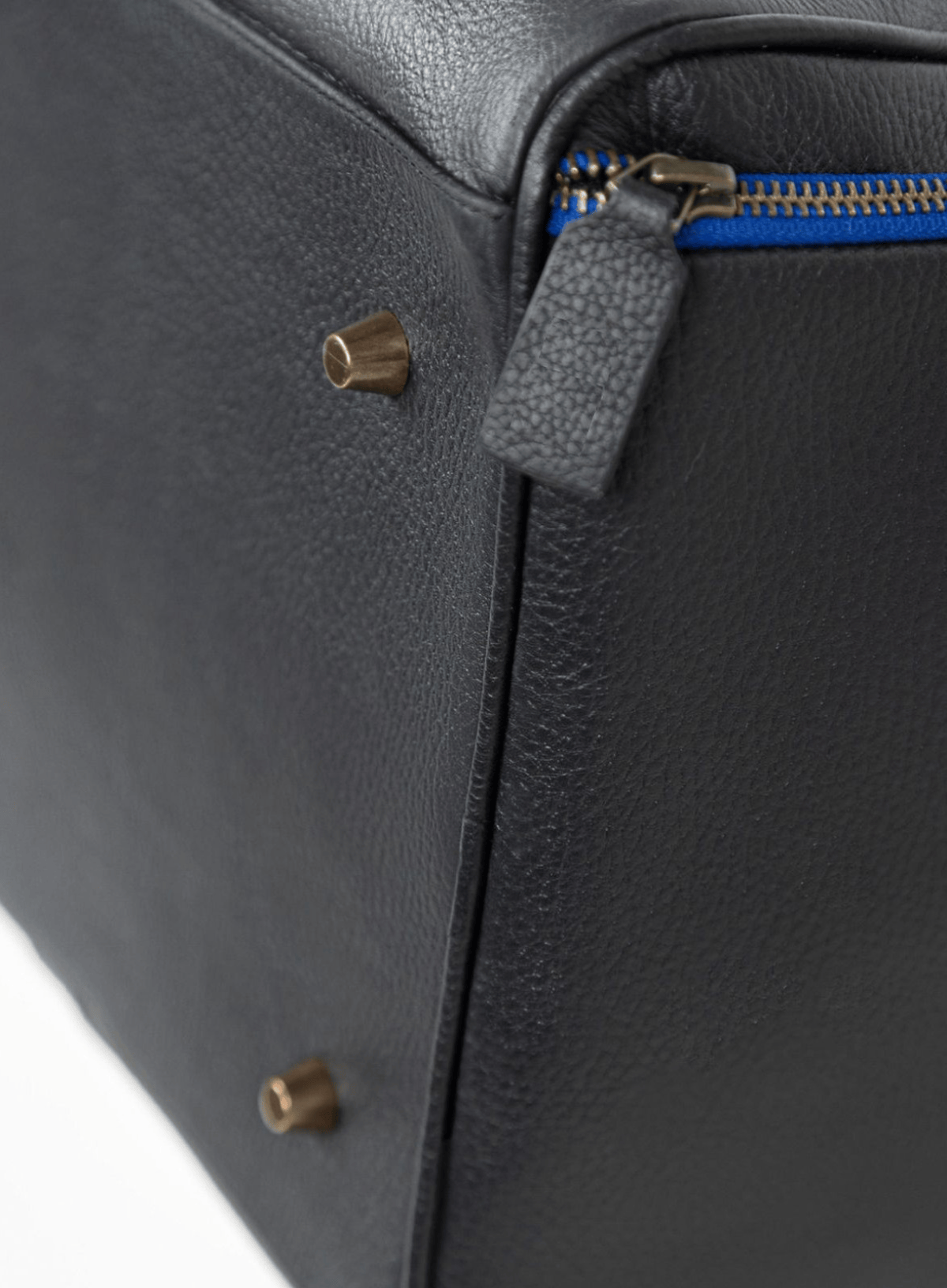 Close-up of a dark gray leather bag with gold zipper pulls and blue zipper.