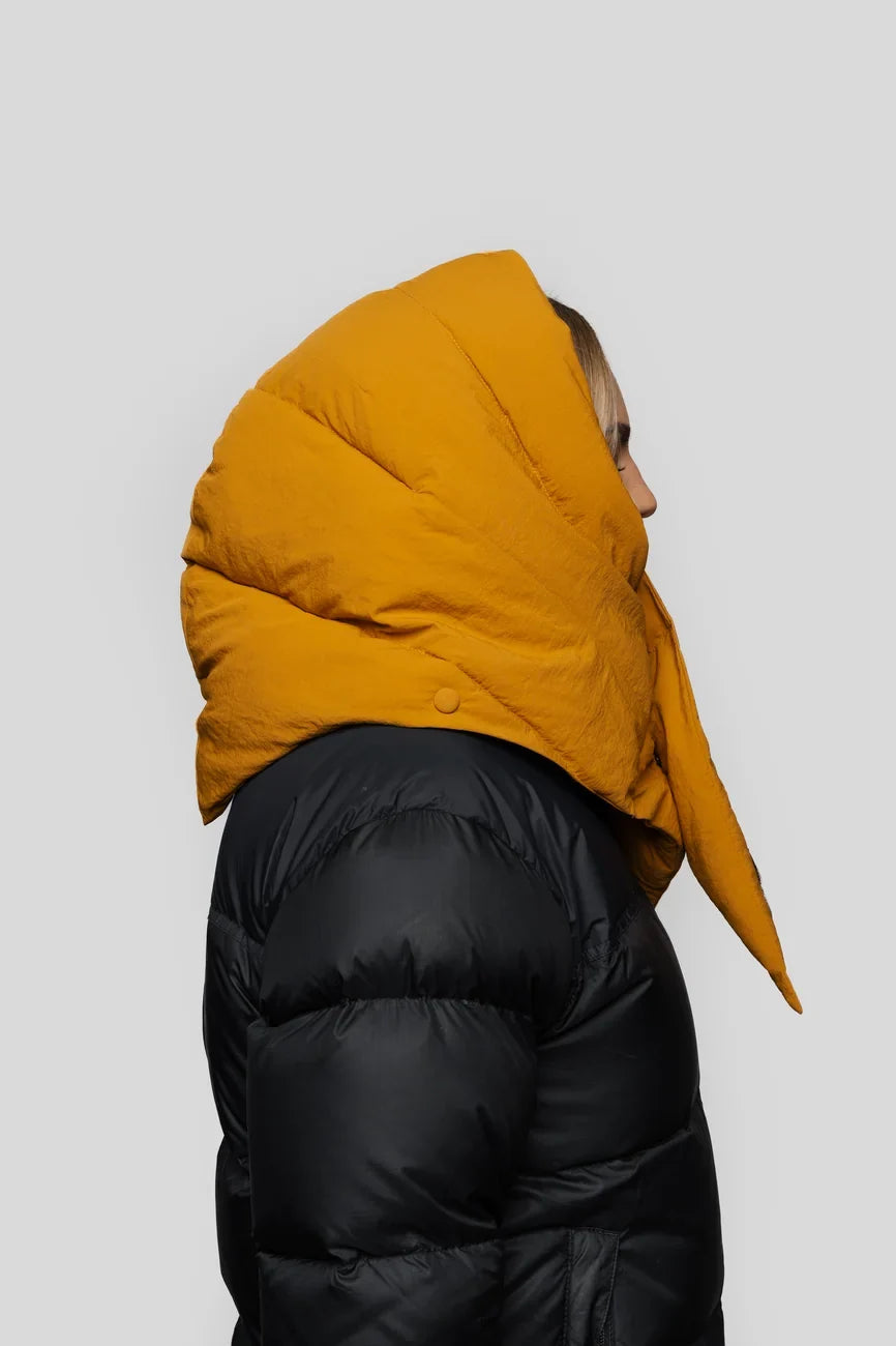 Amber yellow vegan puffer hood with pointed tip, made from recycled materials, worn over black jacket. - The New Orchard - Amber Yellow