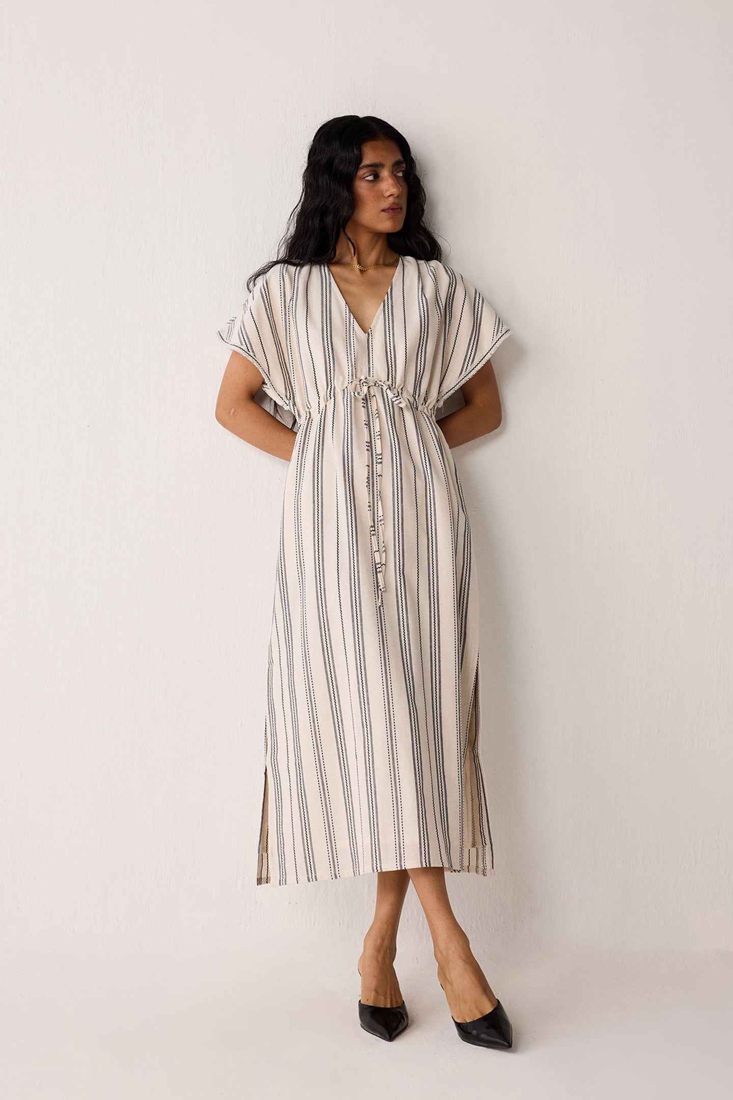 Woman wearing a striped dress against a plain background